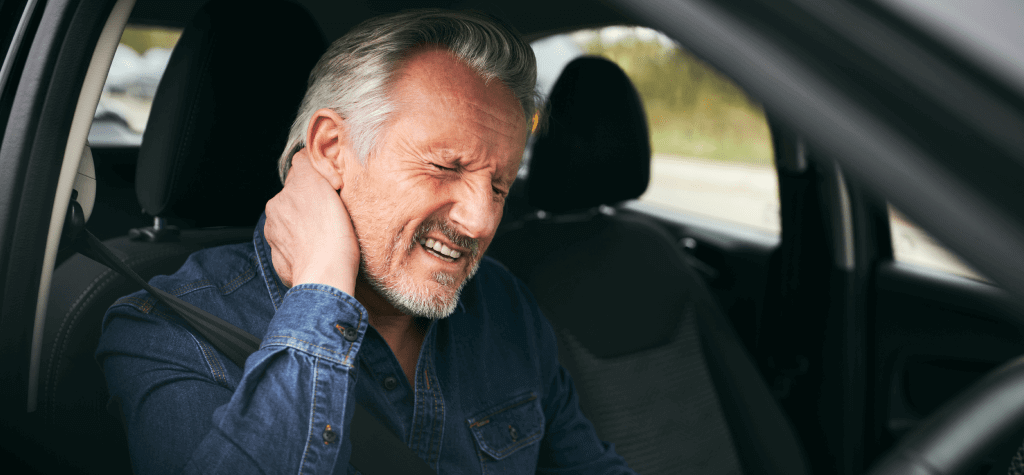 A man grasps at the back of his neck in pain