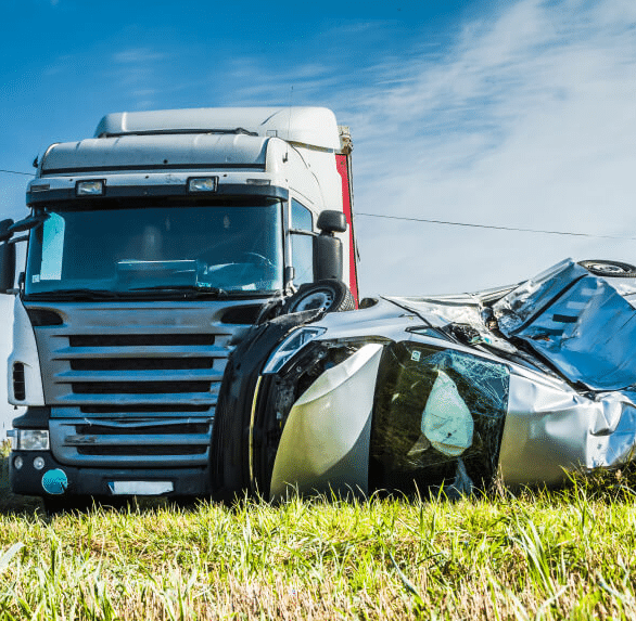 A crumbled car lays wrecked next to a semi truck in a field