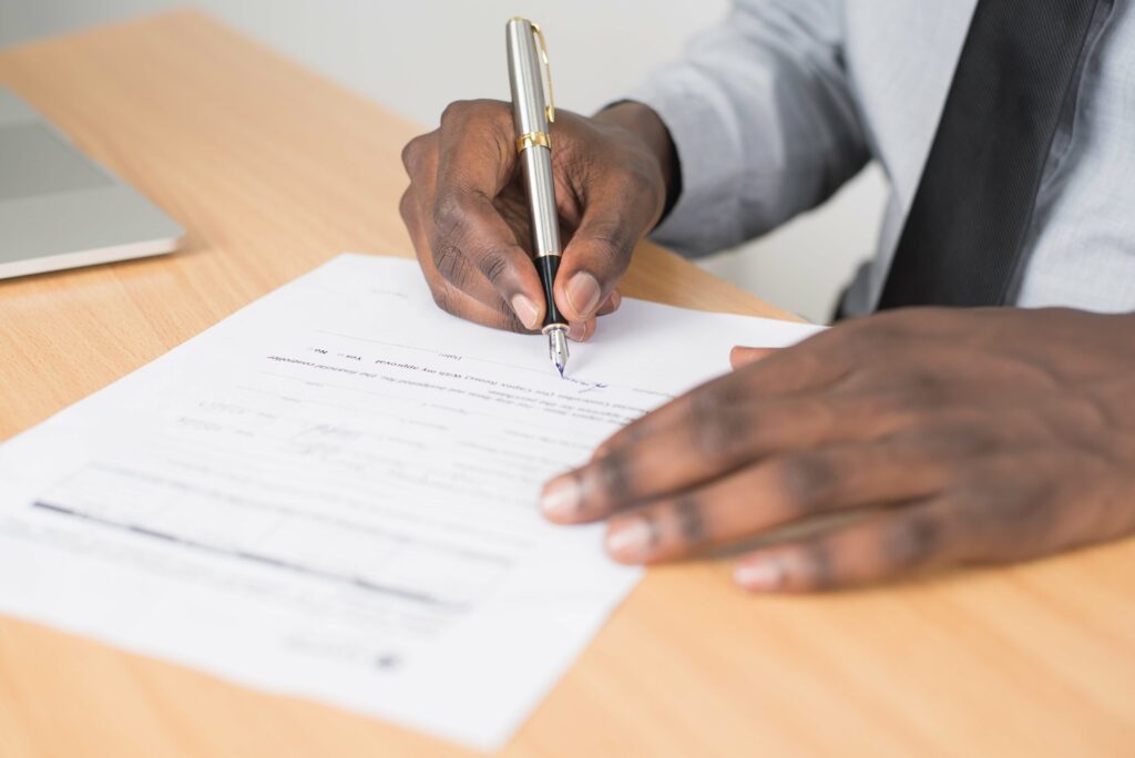 A close up of a person signing a proof of income letter