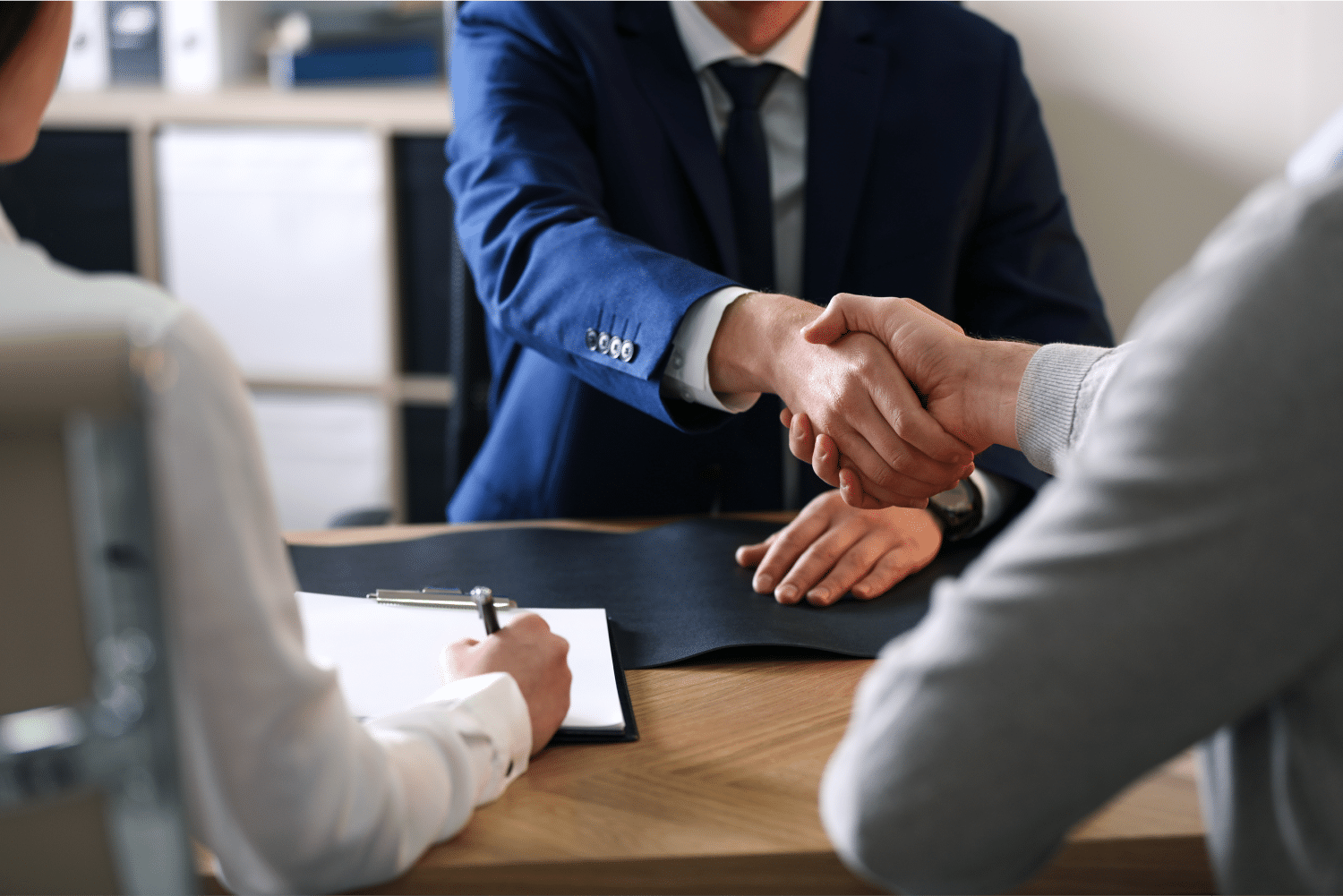 Men shaking hands at desk in meeting