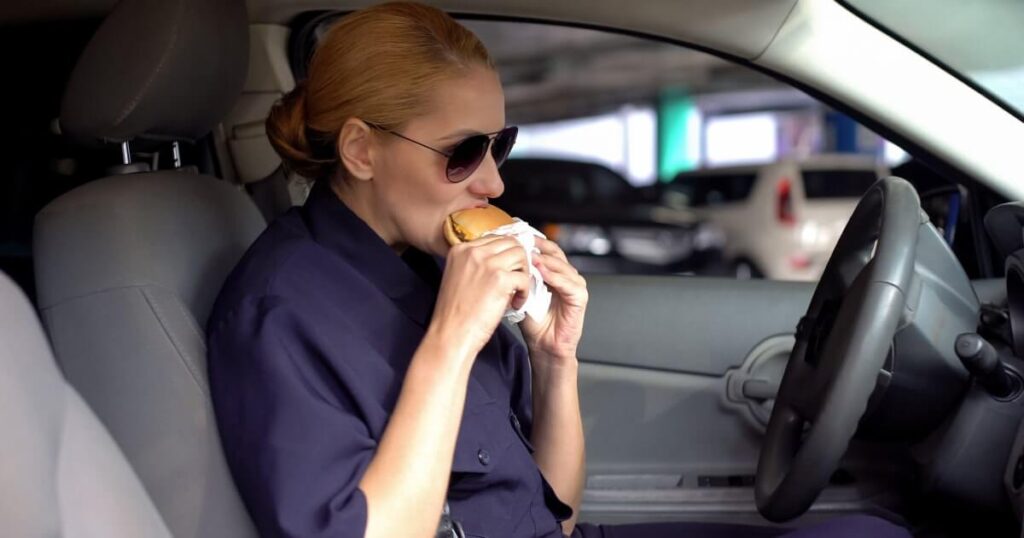 A woman eats a burger in her car