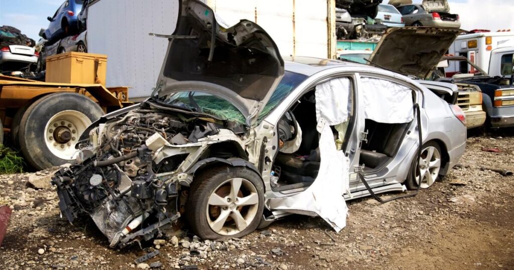 A totaled car with its engine falling out