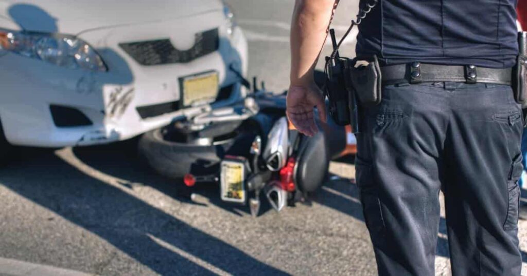 A police officer approaches a motorcycle accident with a car