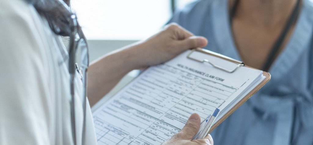 Healthcare worker holding a clipboard with an insurance claim form
