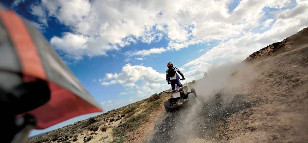 Two people riding ATVs on a rugged trail